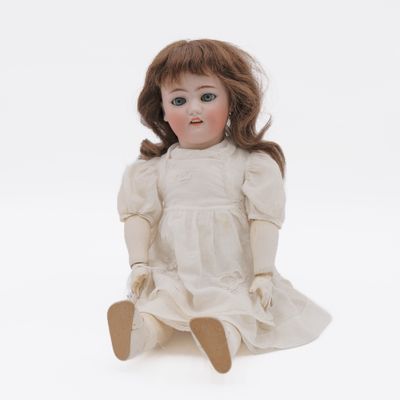 a close up of a doll sitting on a white surface
