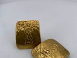 a close up of two gold dice pieces on a white surface