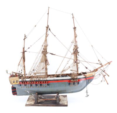 maquette en bois d'un voilier posée sur un socle, sur une surface blanche
