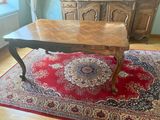 une grande table en bois posée sur un tapis rouge dans une pièce