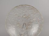 une assiette blanche ornée d'un motif, posée sur un socle