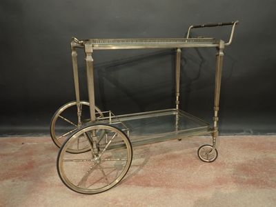 un chariot de bar ancien en laiton, avec des étagères en verre et des roulettes