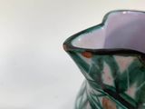 a green and white vase and a cup on a table