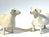 deux moutons blancs debout l'un à côté de l'autre sur une surface blanche