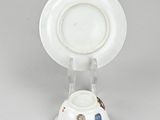 underside view of a plate and saucer on a stand on a grey surface
