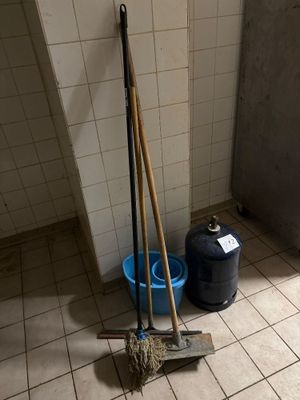 deux balais et une serpillière posés par terre dans une salle de bains