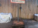 un barbecue posé sur une terrasse en bois, avec une pancarte dessus