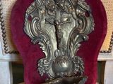 a silver statue on a red velvet cushion on a chair