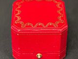 a small red box with a gold decoration on it