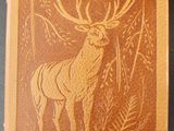 un vieux livre sur lequel figure un cerf, posé sur une table