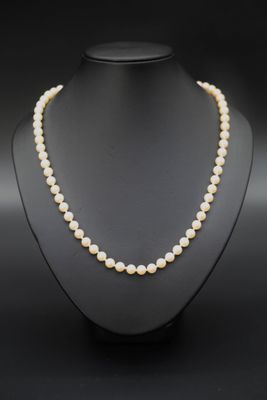 un collier de perles blanches sur un mannequin noir