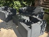 grey wicker patio furniture set on patio with trees in background