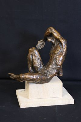 statue of a woman sitting on a marble block with her hands in the air