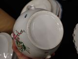 a person holding a white tea pot with flowers on it