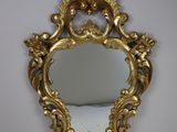 un miroir au cadre doré ouvragé, orné d'un motif décoratif sur le pourtour