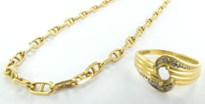 un gros plan sur un collier en or et une bague posés sur une surface blanche