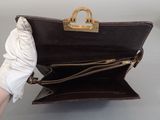 a person holding a brown purse with a gold handle