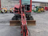 a red tractor parked in a parking lot next to a building