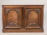 une vieille armoire en bois à deux portes, ornée de sculptures sur la façade