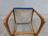 a wooden chair with a blue seat sitting on a cement floor