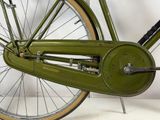 a green bicycle that is leaning against a wall
