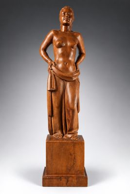 une statue en bois représentant un homme debout sur un socle