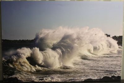 une photo représentant une grande vague qui s'écrase sur la plage