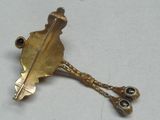 une broche en or ornée d'une feuille, posée sur une table