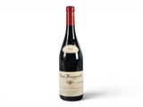 a bottle of red wine sitting on top of a white surface