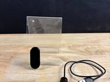 un petit objet noir posé sur une table à côté d'un chargeur