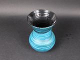 a small blue vase sitting on a black surface