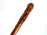 un gros plan sur une canne en bois sur laquelle est sculpté un homme