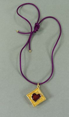 un gros plan sur un collier violet orné d'un cœur