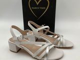 a pair of white sandals with silver straps and a black box