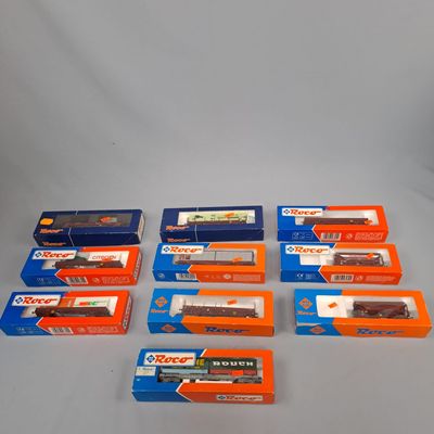 six boîtes contenant des trains miniatures, posées sur une surface blanche