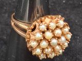 pearl and gold ring on a black cone on a black surface