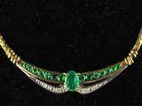 a close up of a necklace with a green stone on it