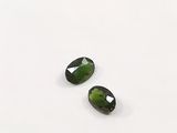 a pair of green tourmaline gems on a white surface