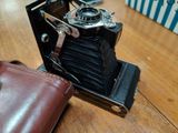 an old camera sitting on a wooden table next to a wallet