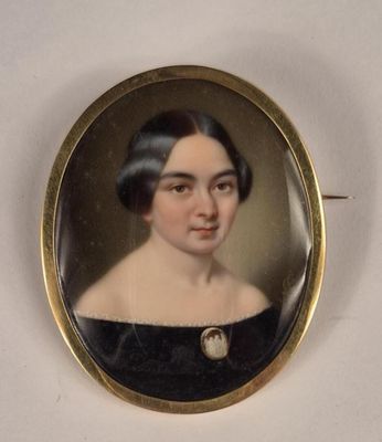 une vieille photo d'une femme en robe noire portant une broche en perles