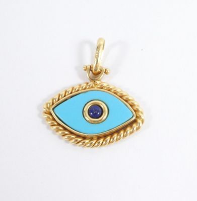 a close up of a blue evil eye pendant on a white surface