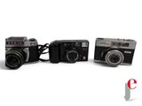 three cameras sitting next to each other on a white surface