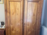 a wooden armoire in the corner of a room