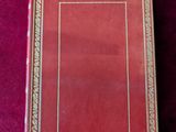 un livre rouge posé sur une table recouverte d'un tissu violet