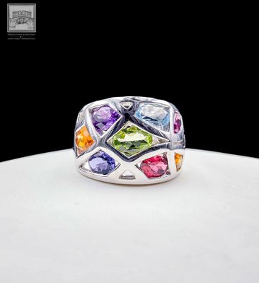a close up of a ring with multi colored stones on a white surface