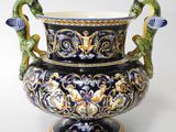 a blue vase with two birds on it and a bird on the handle