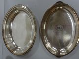 two oval silver trays on a table with a remote control