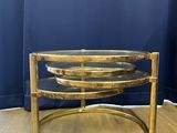 a brass coffee table with three glass shelves on top of it