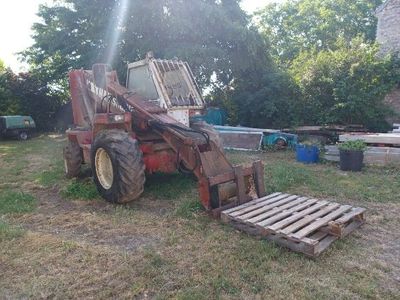 a tractor that is sitting in the grass with a pallet