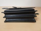 three black leather wallets stacked on top of each other on a table